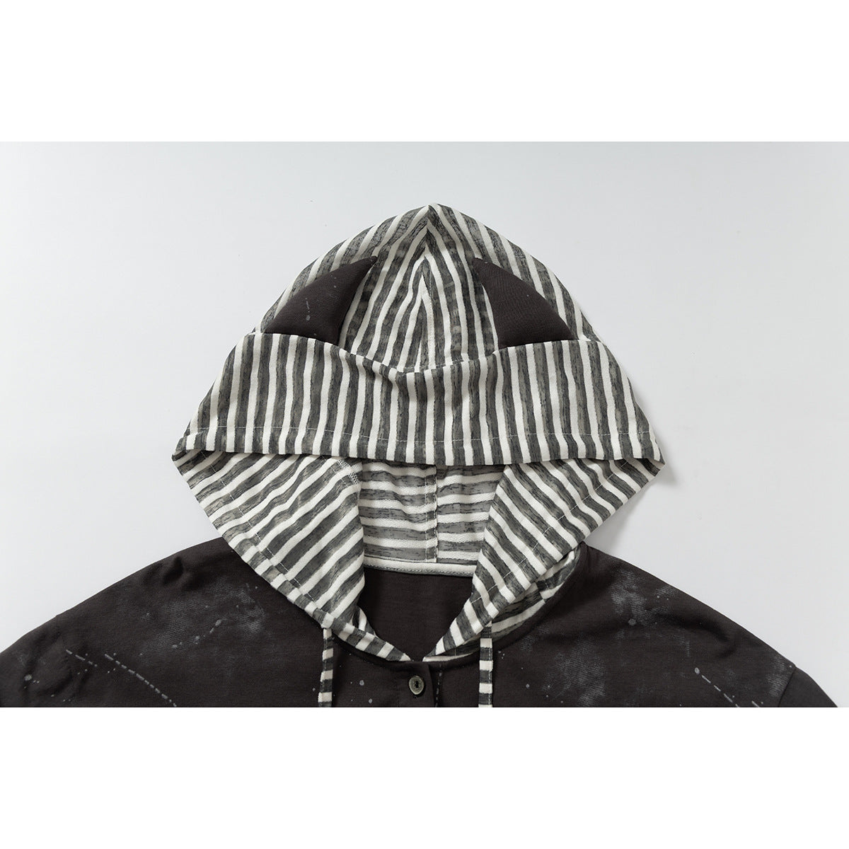 Close-up of a dark garment's hood, lined with gray and off-white stripes and paired with striped drawstrings.