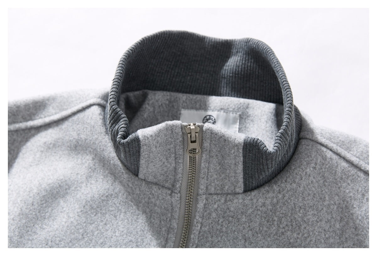 Close-up of a light gray coat's dark ribbed stand collar and front zipper.