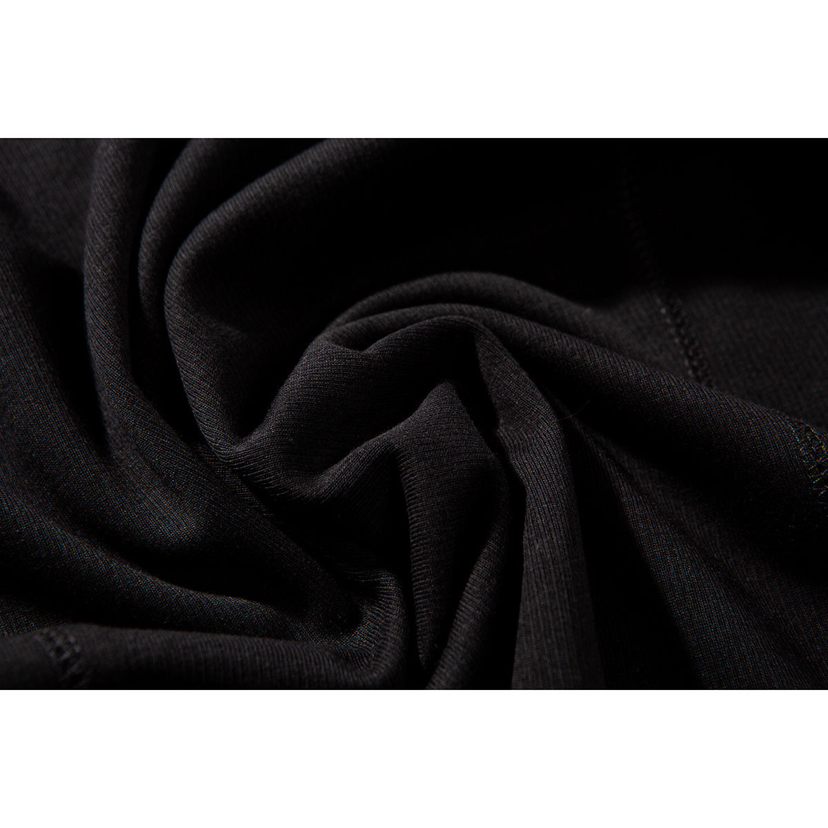 Macro view of black fabric gathered into folds, showing its surface texture and stitching.