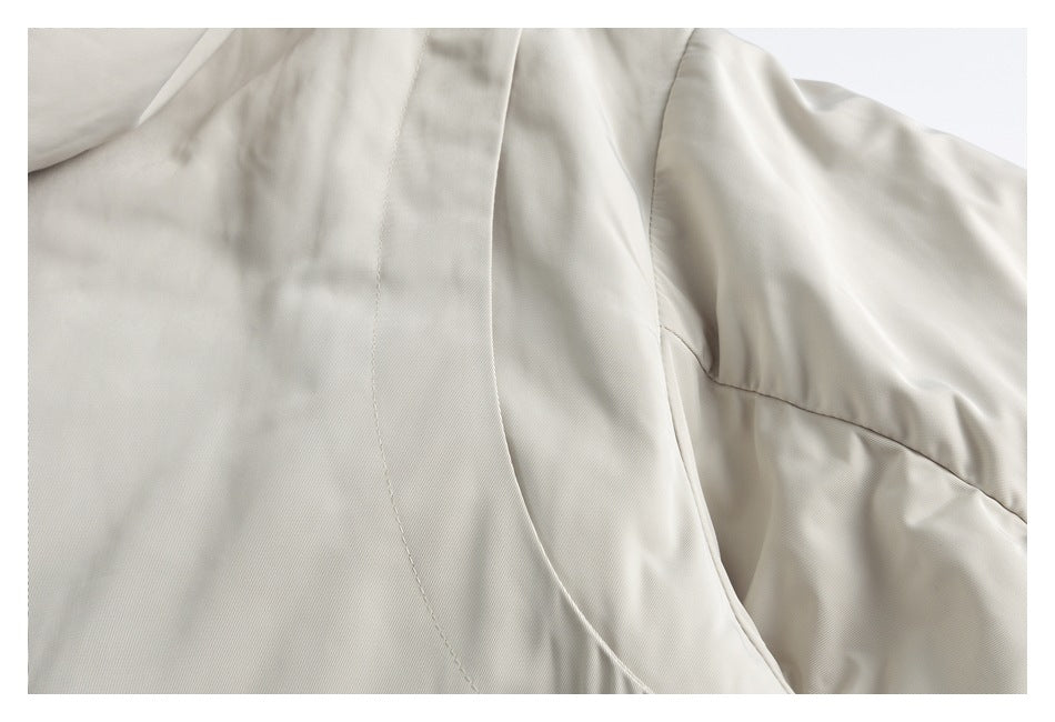 Close-up of an ivory garment showing curved seams and a sleeve.