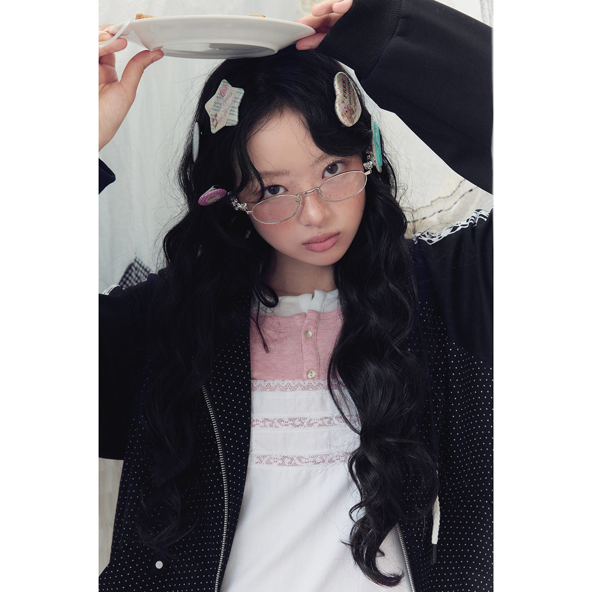 Close-up of a model wearing a black dotted hoodie with white sleeve trim over a pink-and-white dress.