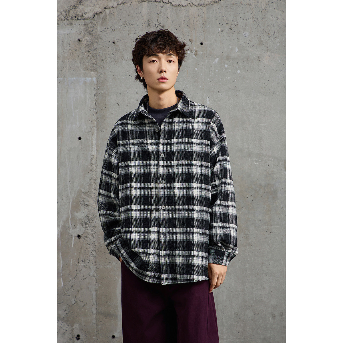 Model wearing a black-and-white plaid button-up shirt over a dark top, shown from the front.