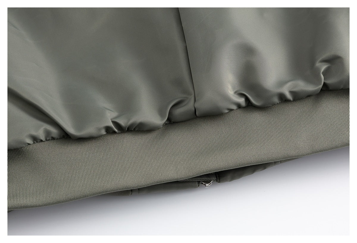 Close-up of the olive-gray jacket's gathered hem, wide ribbed waistband, and zipper.