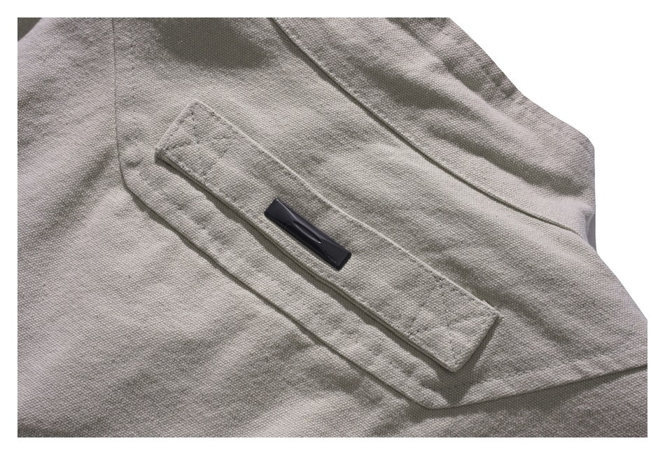 Close-up of a light gray jacket pocket with a flap and small black rectangular tab.