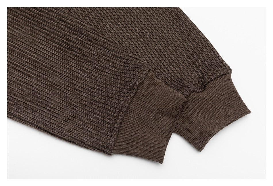 Close-up of a dark brown knit sleeve ending in a wide ribbed cuff.