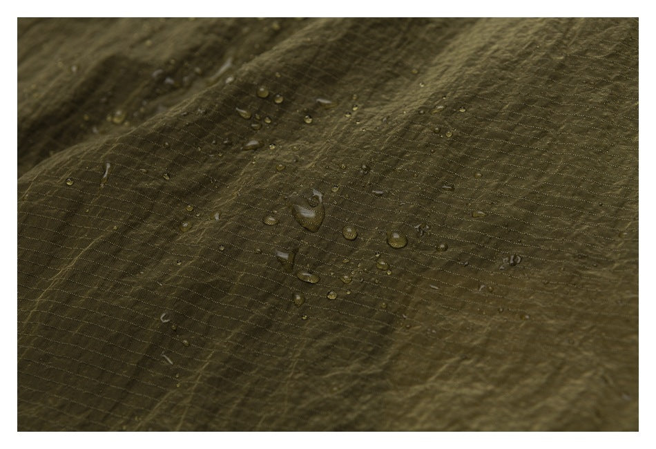 Water droplets bead on the textured olive fabric in a close-up.