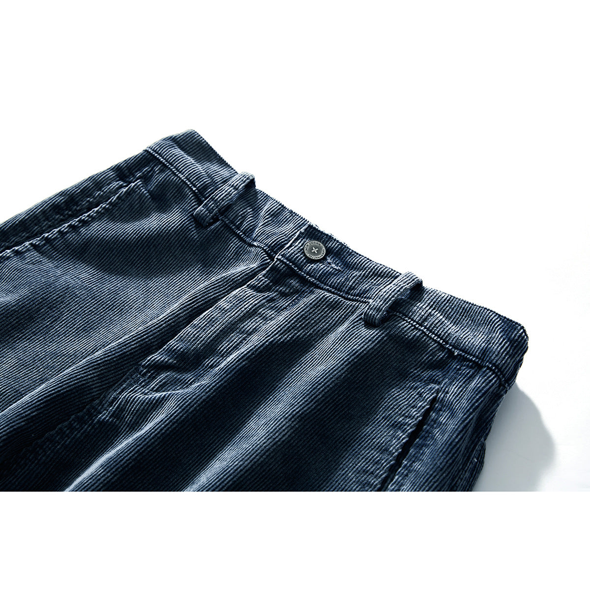 Close-up of dark blue corduroy trousers showing the waistband, button, belt loops and front pocket.