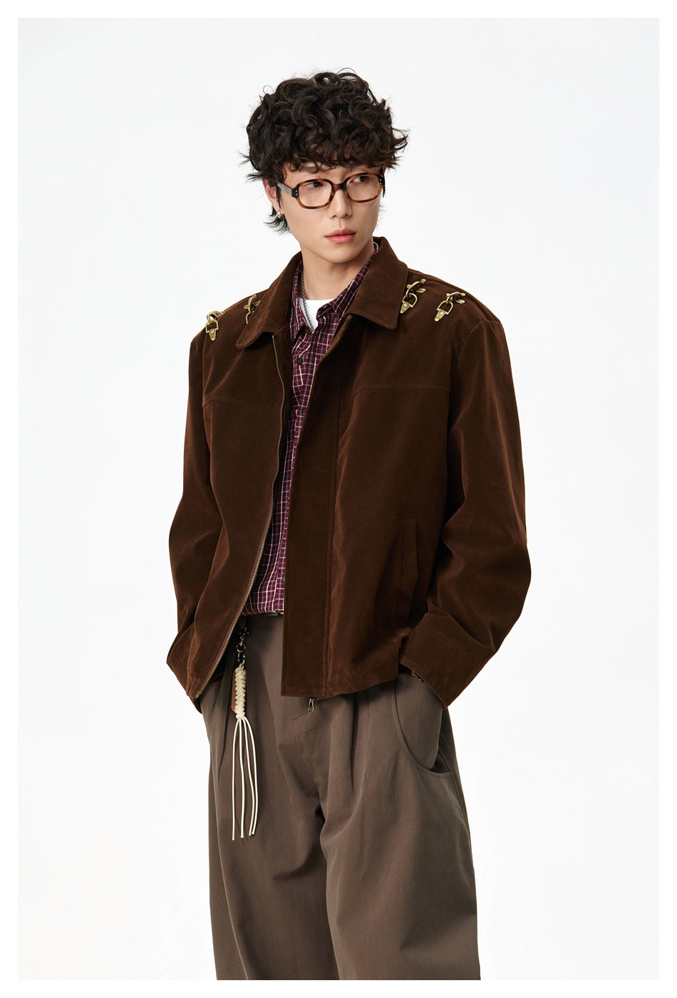 Three-quarter front view of a model wearing a dark brown jacket with gold shoulder hardware and a burgundy plaid shirt.