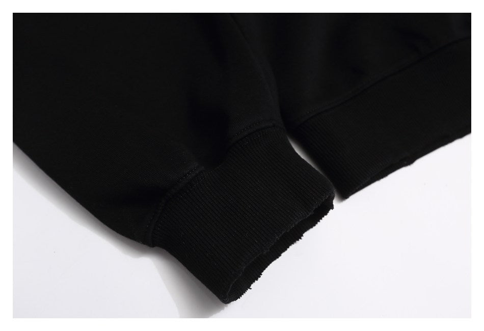 Close-up of black ribbed sweatshirt cuffs and stitched seams on a white background.