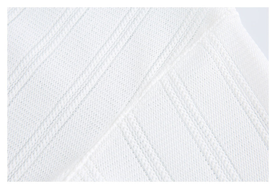 Macro view of white knit fabric showing alternating textured and open stitch patterns.