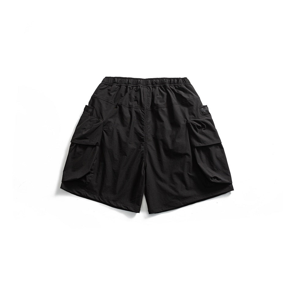 Back view of black cargo shorts with an elastic waistband and large flap pockets on both legs.
