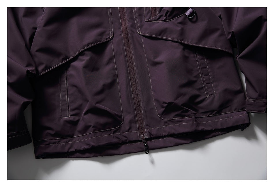 Close-up of the dark plum jacket's lower front, showing the central zipper, large pockets, and stitched hem.