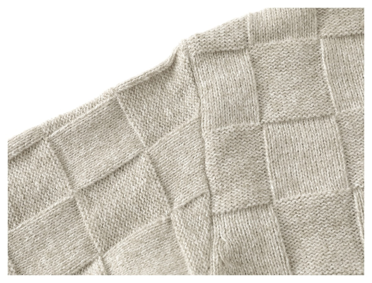 Close-up of the light beige cardigan’s shoulder and alternating textured knit panels.