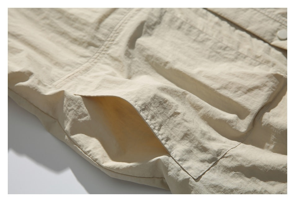 Close-up of a large patch pocket and stitched seams on the light beige jacket.