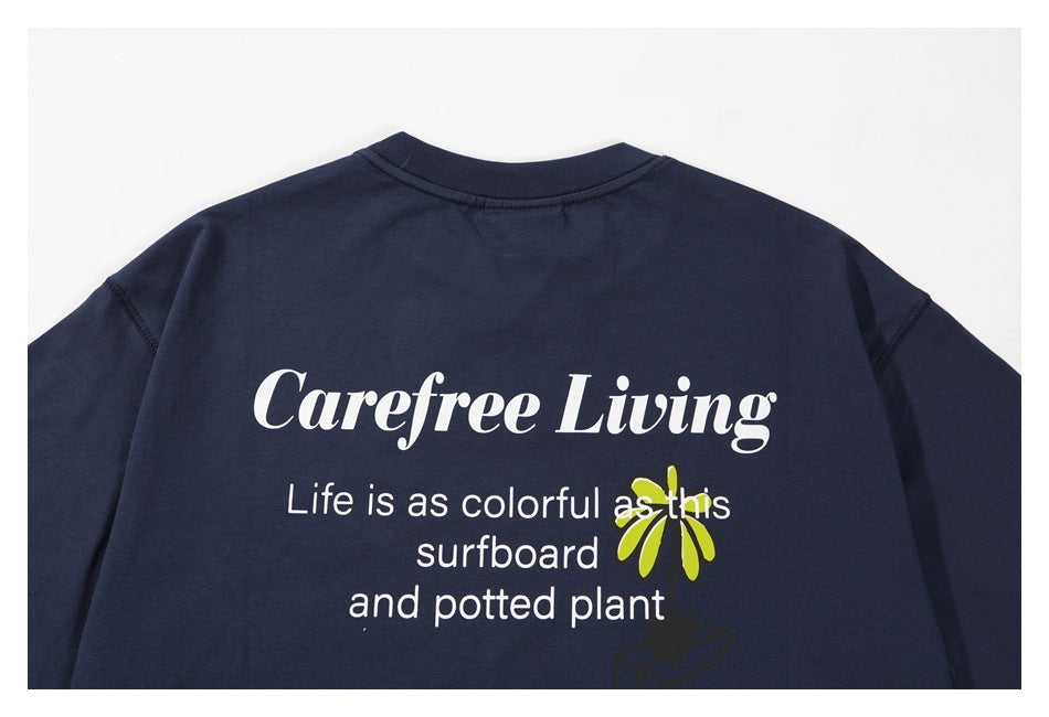 Back of a navy T-shirt with white “Carefree Living” text and a lime-green plant graphic.
