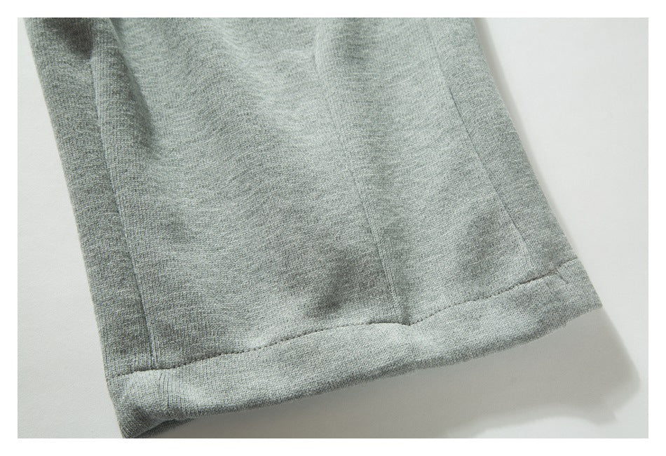 Close-up of a light gray knit garment's stitched hem and seam on a white background.