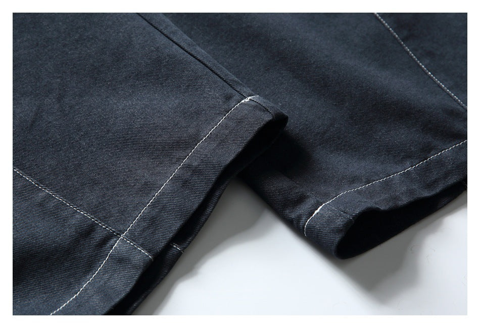 Close-up of dark denim trouser hems with contrasting light stitching.