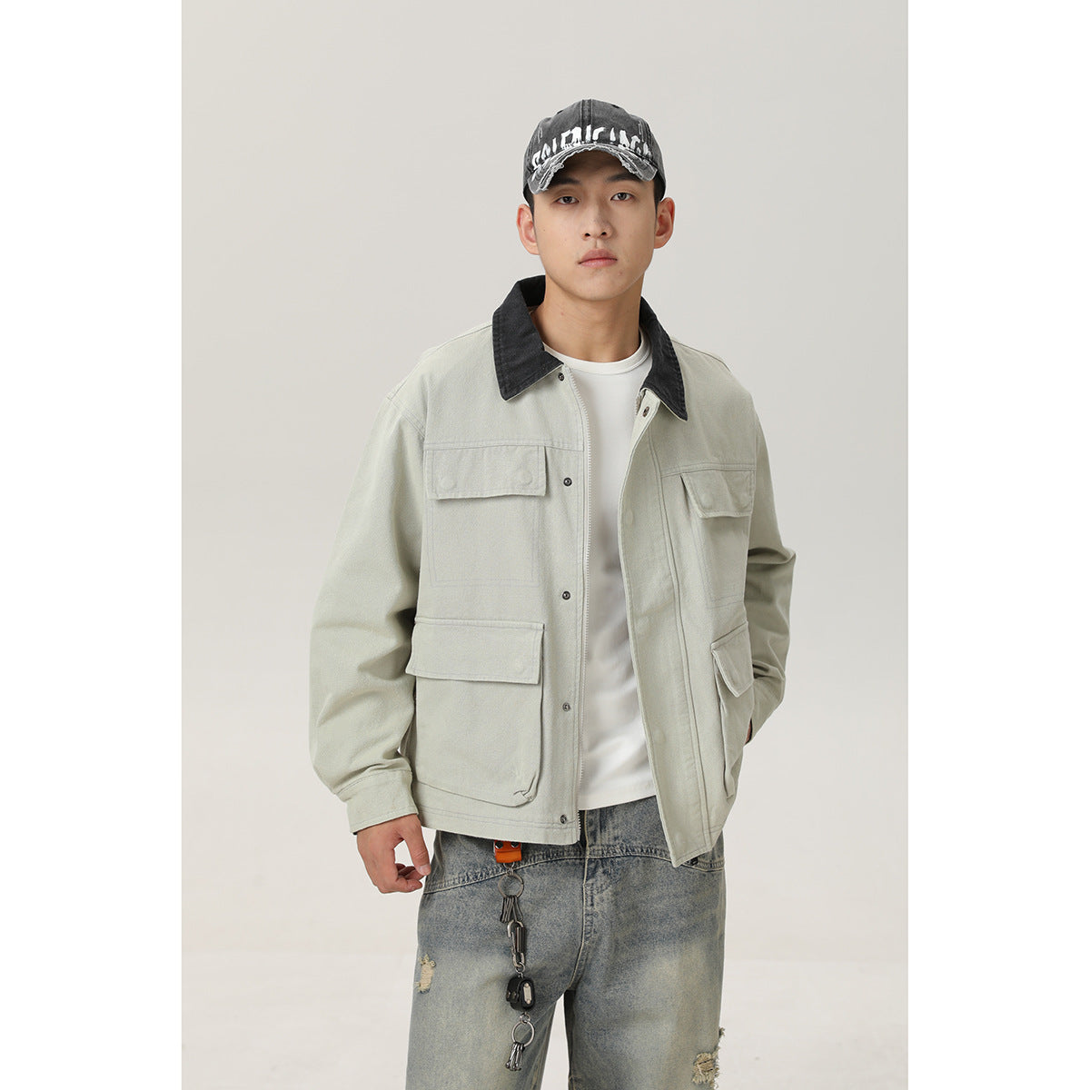 Front view of a model wearing a pale sage utility jacket with a contrasting black collar and four flap pockets.