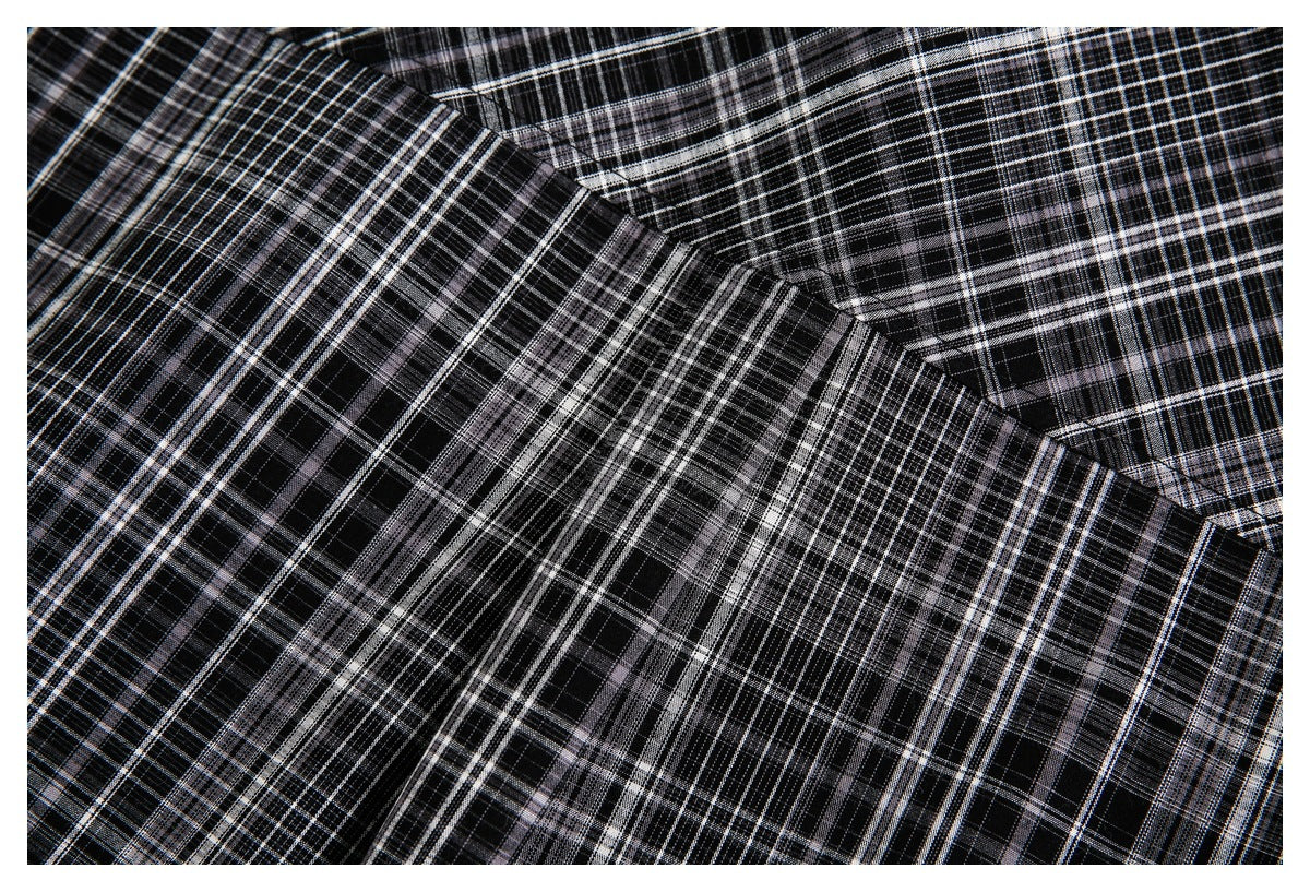 Close-up of overlapping black, white, and gray plaid fabric with visible seams.