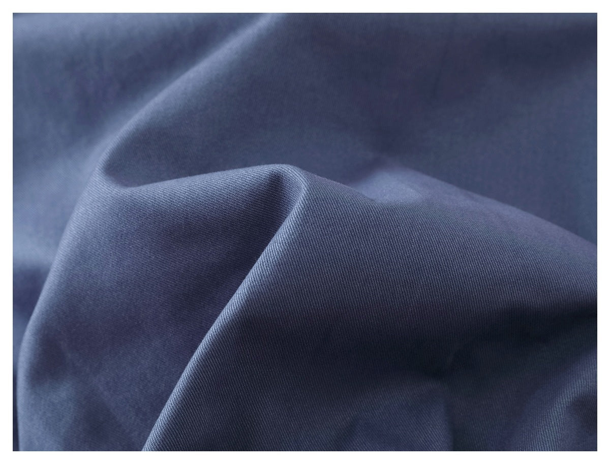 Close-up of softly folded blue fabric showing its fine diagonal weave.