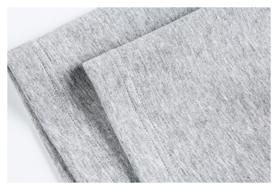 Close-up of light gray heathered fabric with a folded stitched edge.