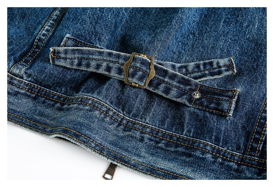 Close-up of a blue denim waist adjuster strap with a metal buckle and snap fastening.