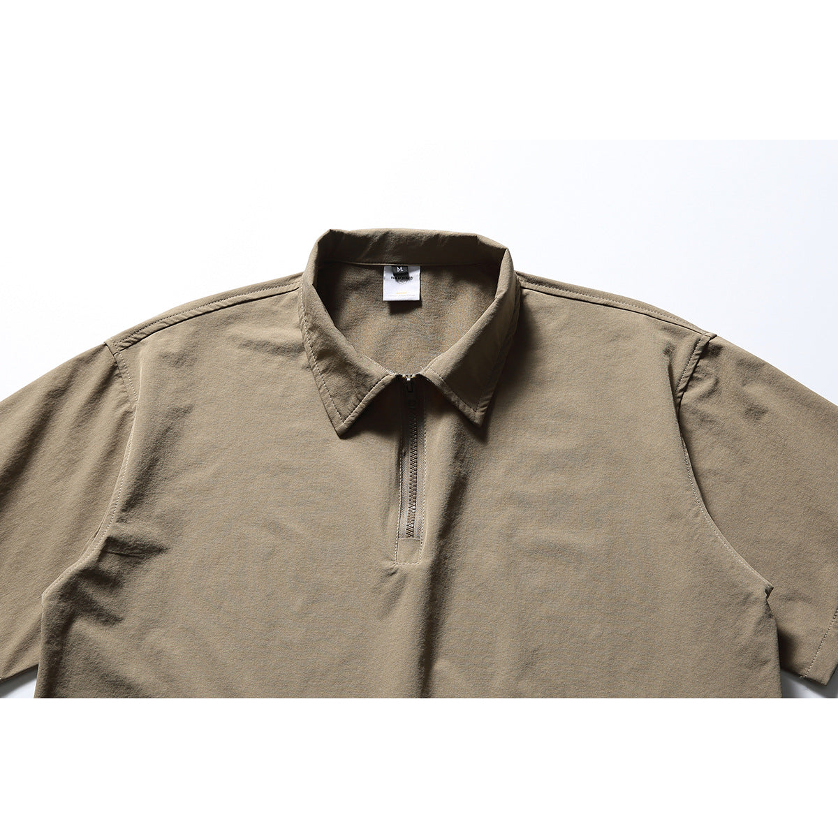 Close-up of a taupe short-sleeve shirt collar and short front zipper.