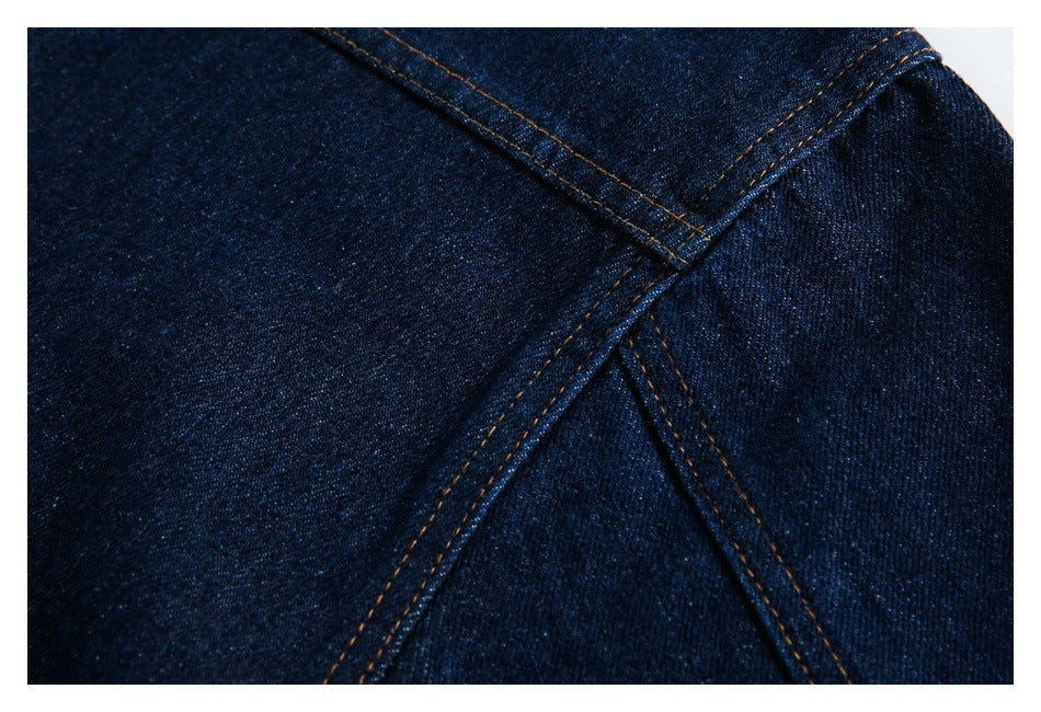 Close-up of dark indigo denim panels joined by orange topstitched seams.