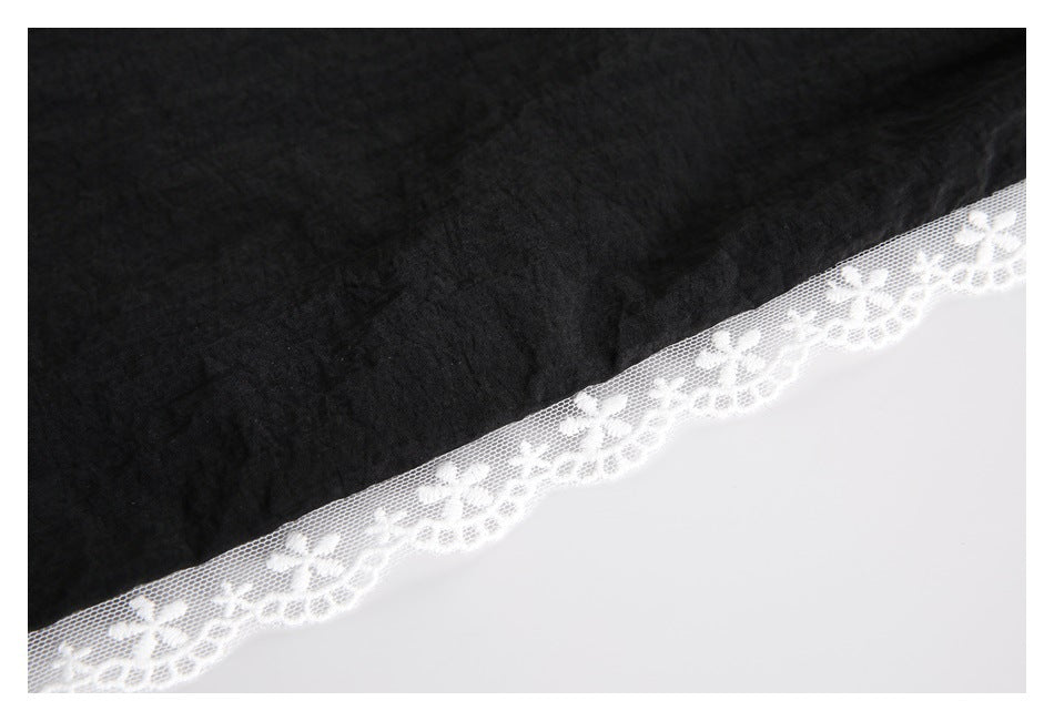 Close-up of white floral lace edging along the hem of black pants.