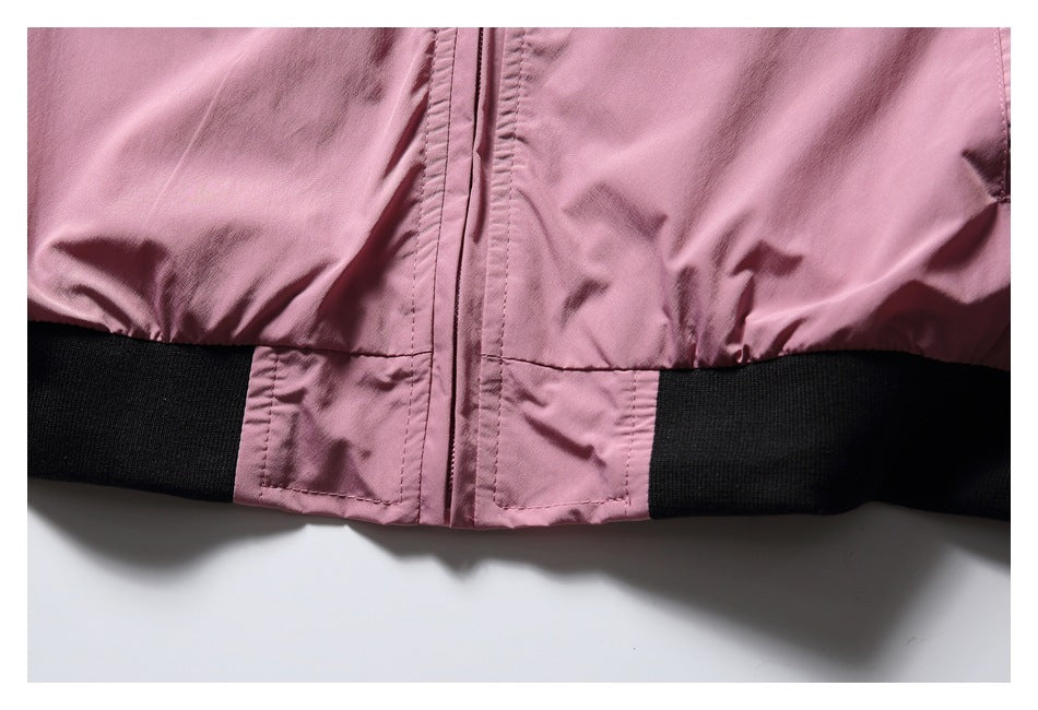 Close-up of the pink jacket's front zipper and black ribbed hem.