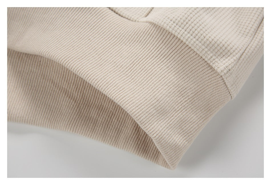 Close-up of the cream top's wide ribbed hem or cuff and textured fabric.