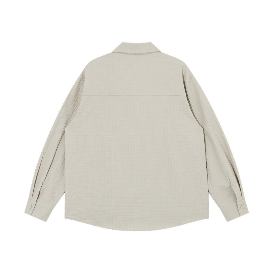 Back view of light gray long-sleeve shirt with yoke seam, textured fabric and buttoned cuffs, flat lay