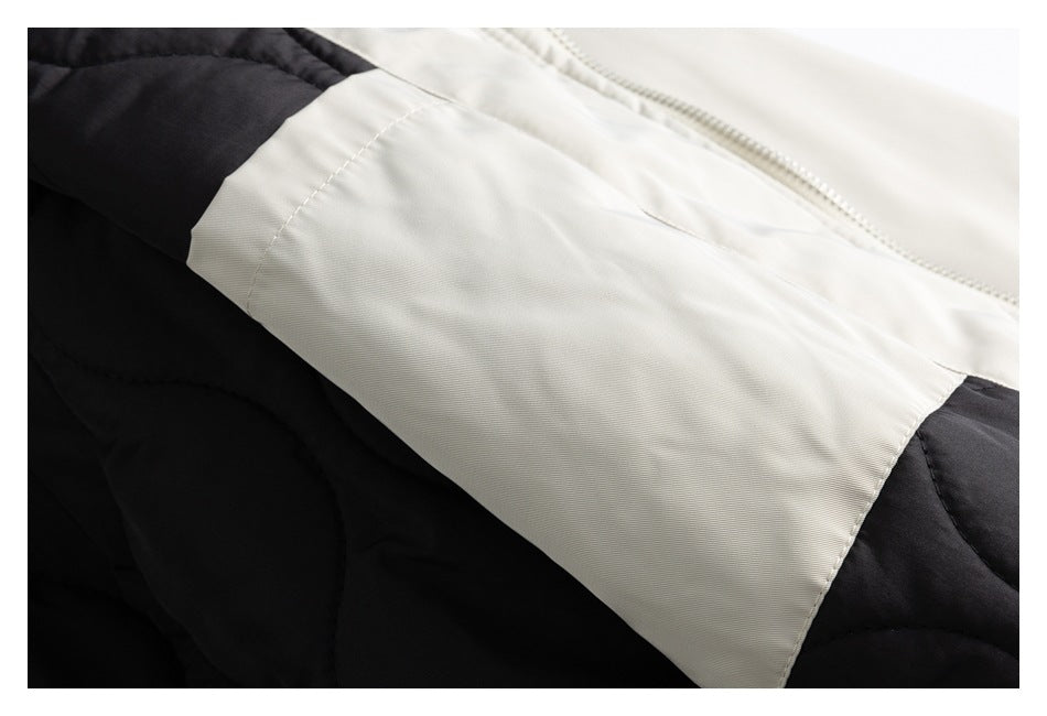 Close-up of an ivory coat panel beside a zipper and black quilted section.