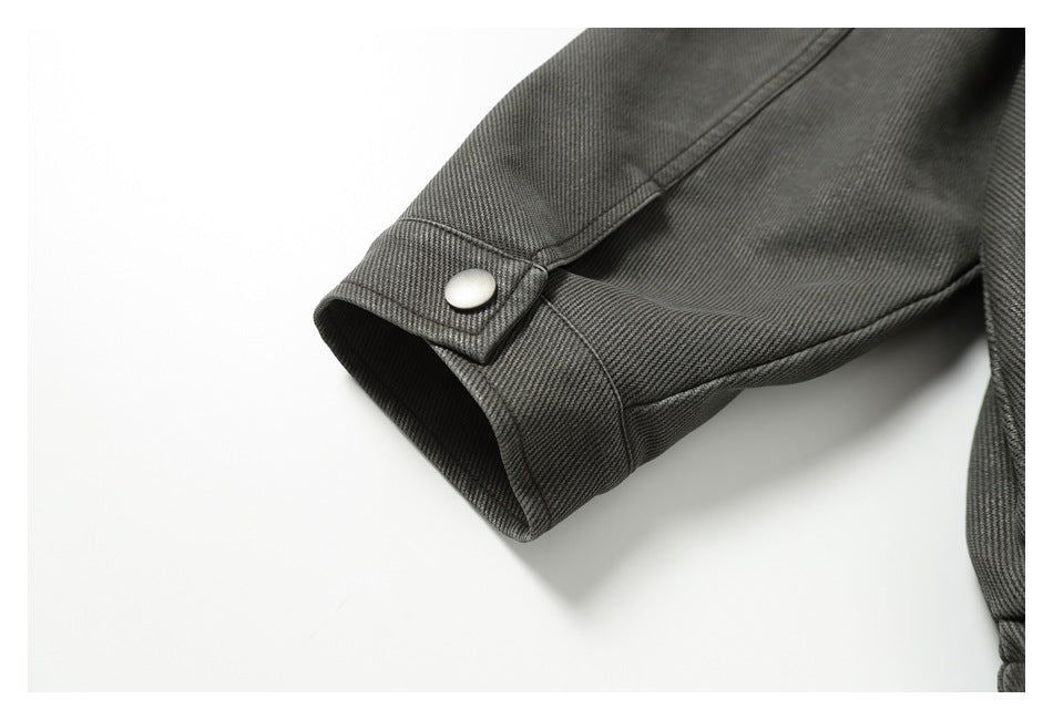 Close-up of a charcoal gray jacket sleeve cuff with a silver snap tab.