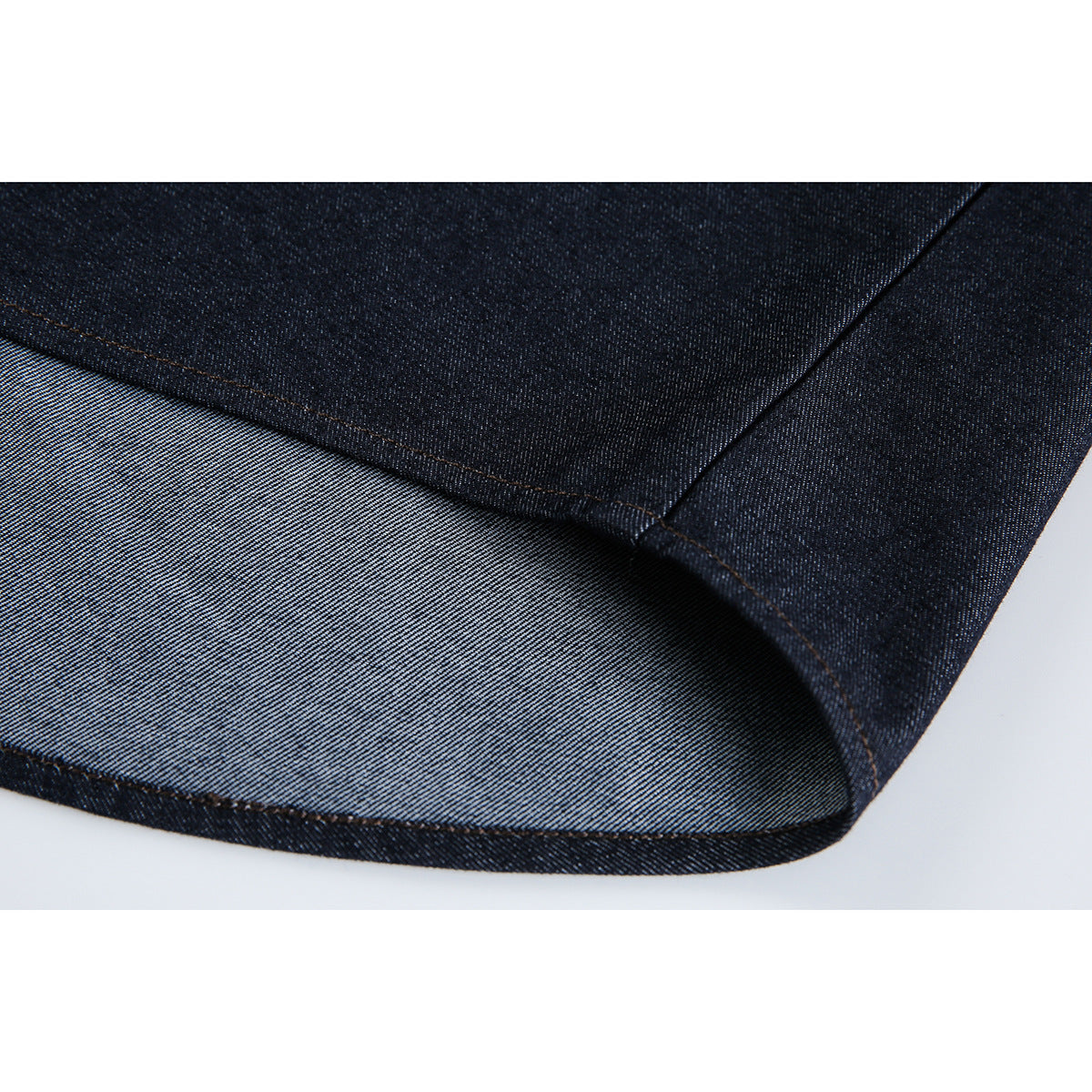 Close-up of a dark denim hem, showing the folded edge, seam stitching, and lighter reverse side.