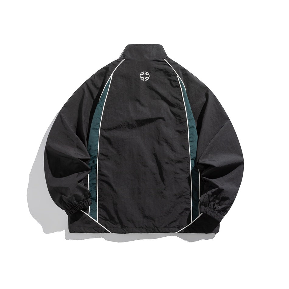 Back view of black jacket with teal side panels, white piping and a small round embroidered emblem below the collar