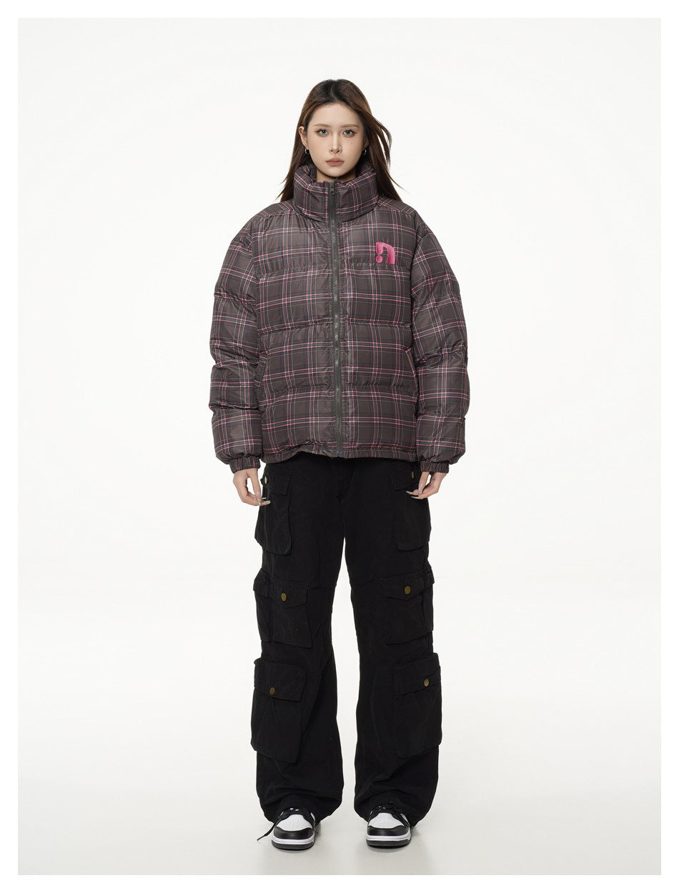 Full-length front view of a model wearing a dark gray plaid puffer jacket with a high collar and black cargo pants.