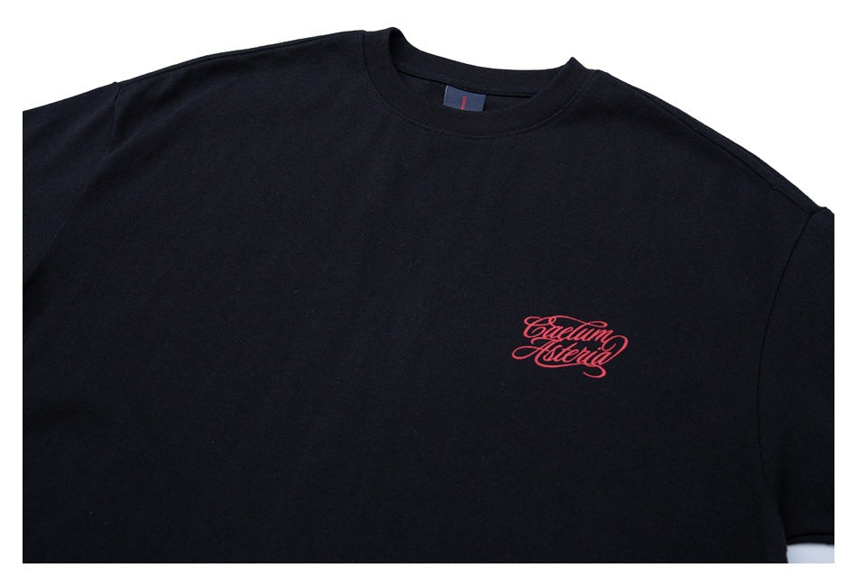 Close-up of a black crew-neck T-shirt showing small red script lettering on the chest.