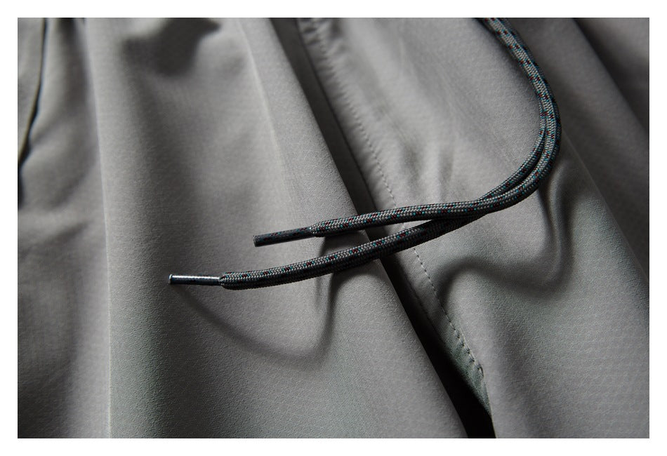 Close-up of gray pants showing dark patterned drawstrings with metal tips.