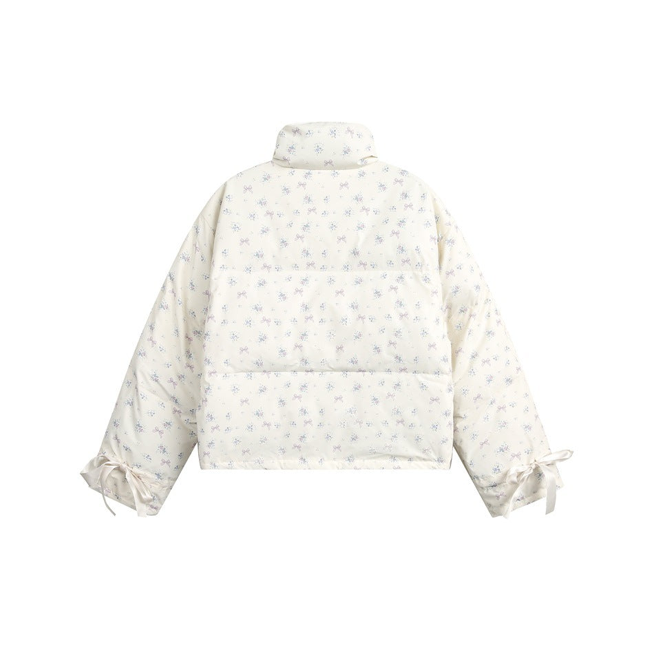 Back of a white jacket with a pastel bow-and-floral print, high collar, and ribbon-tied cuffs, shown flat.