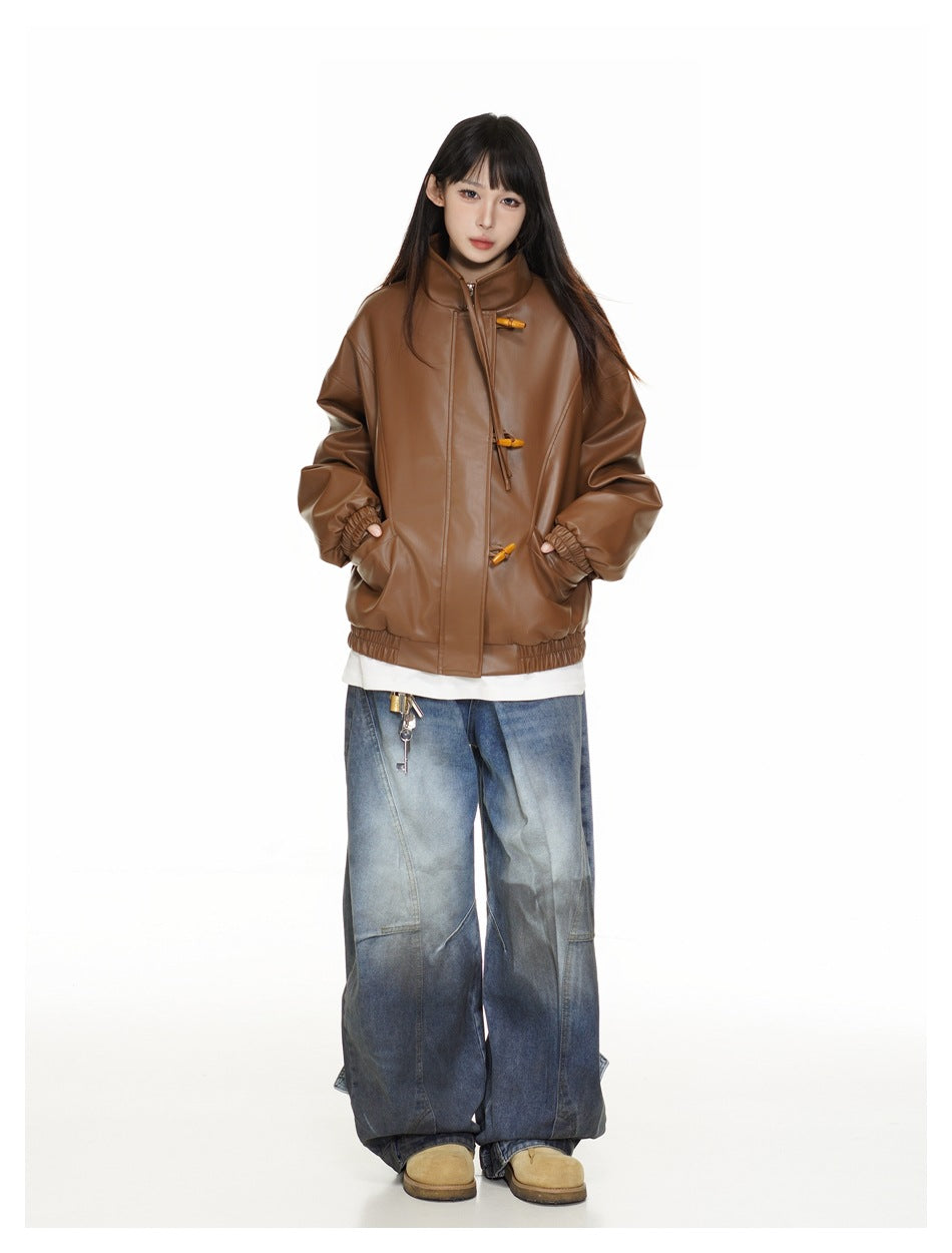 Full-length front view of a model in a brown high-collar jacket with toggle closures and wide blue jeans.