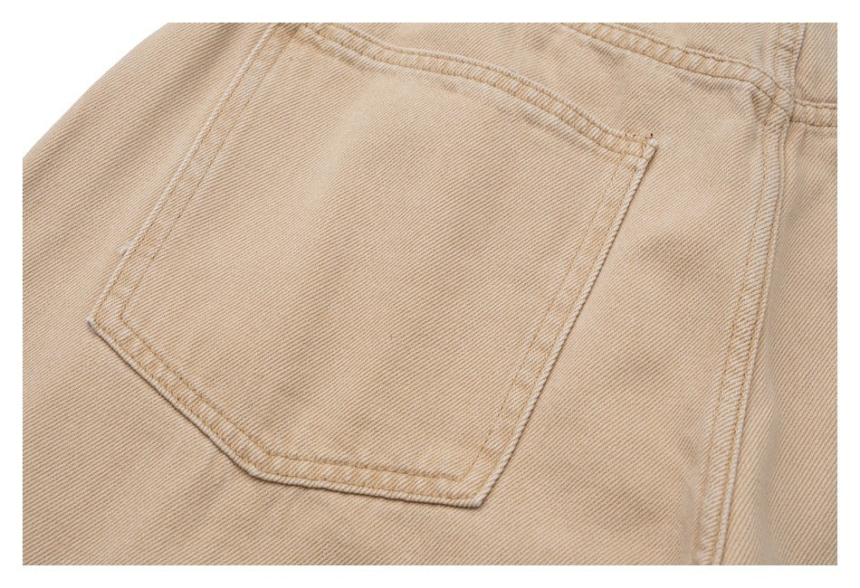 Close-up of a stitched back pocket on beige denim trousers.