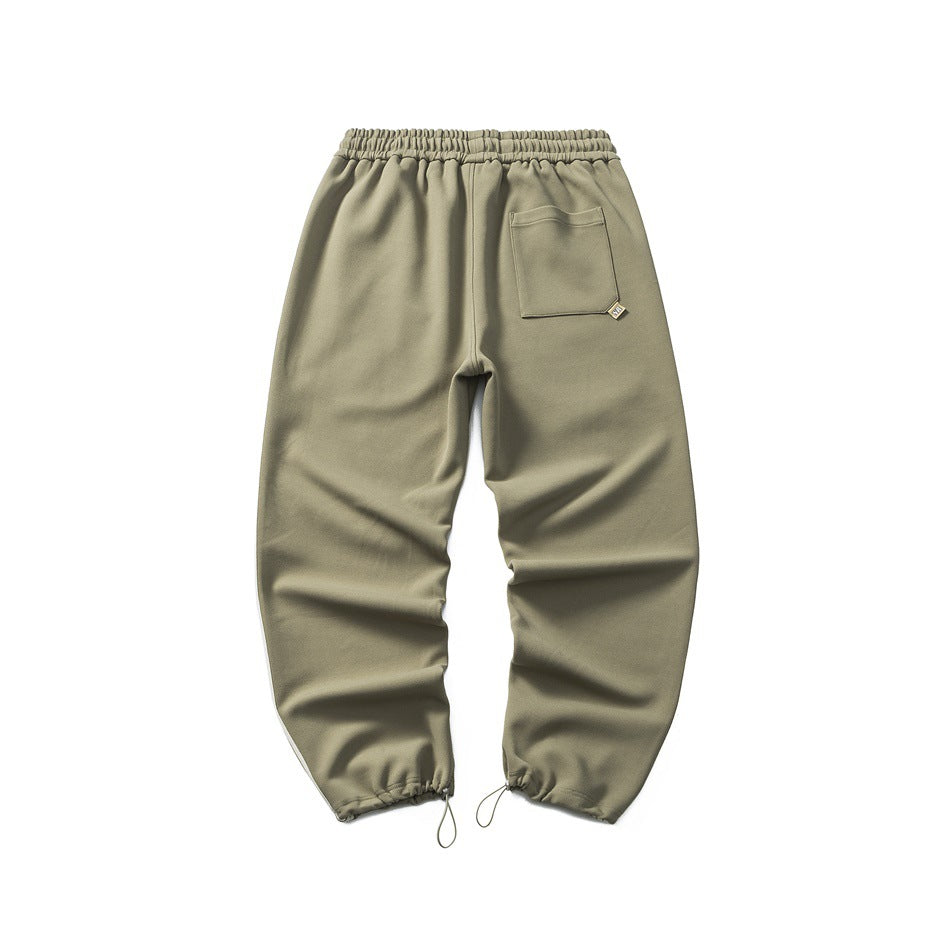 Back view of olive jogger pants with an elastic waist, one patch pocket and gathered drawcord cuffs.