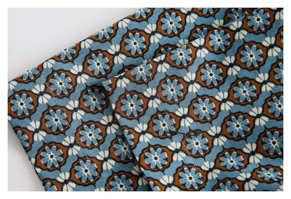 Close-up of overlapping blue floral shirt panels with stitched seams and a folded edge.