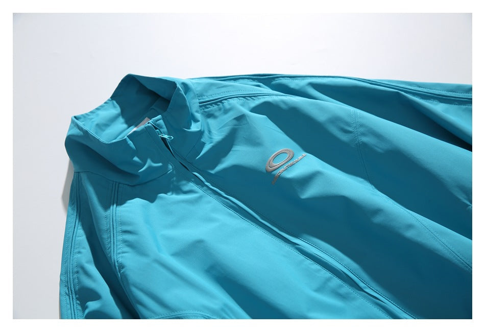 Close view of the turquoise jacket’s front zipper, high collar and small silver embroidered emblem.
