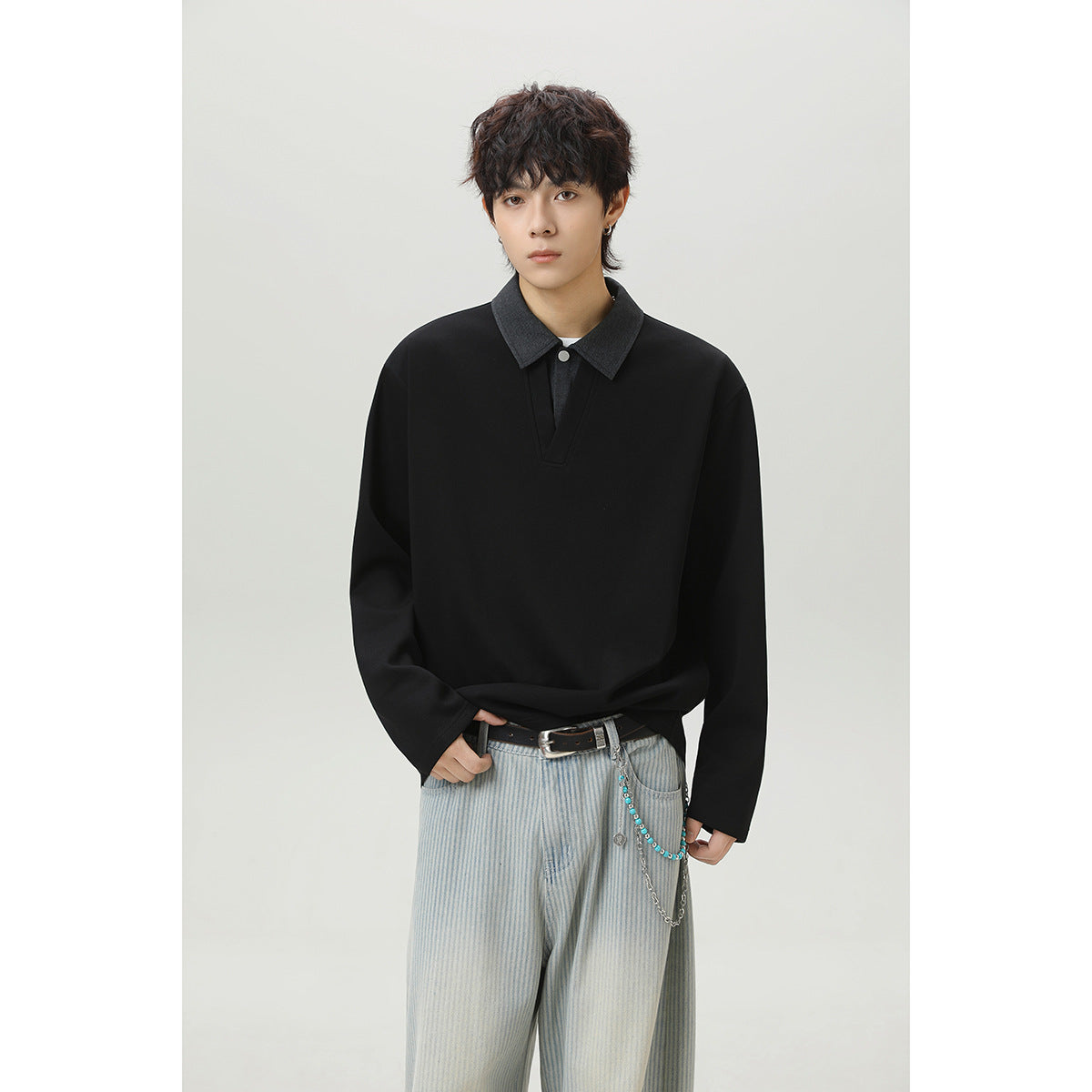 Front view of a person wearing a black long-sleeve top with a charcoal collar and buttoned placket.