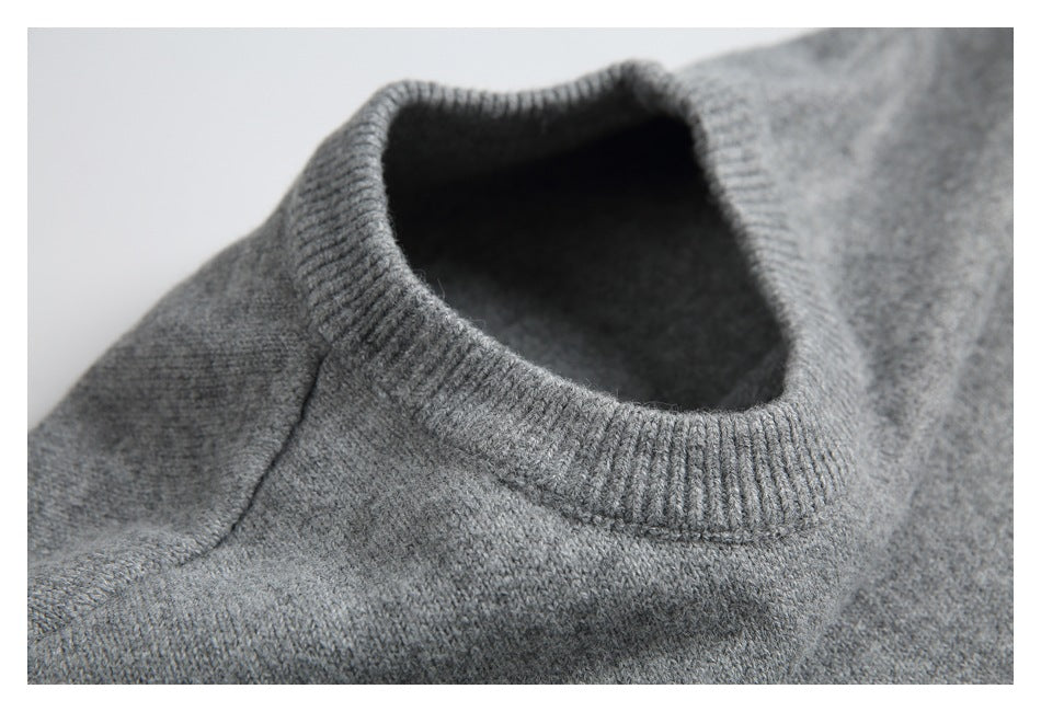 Close-up of a gray sweater's ribbed crew neck and shoulder seam.