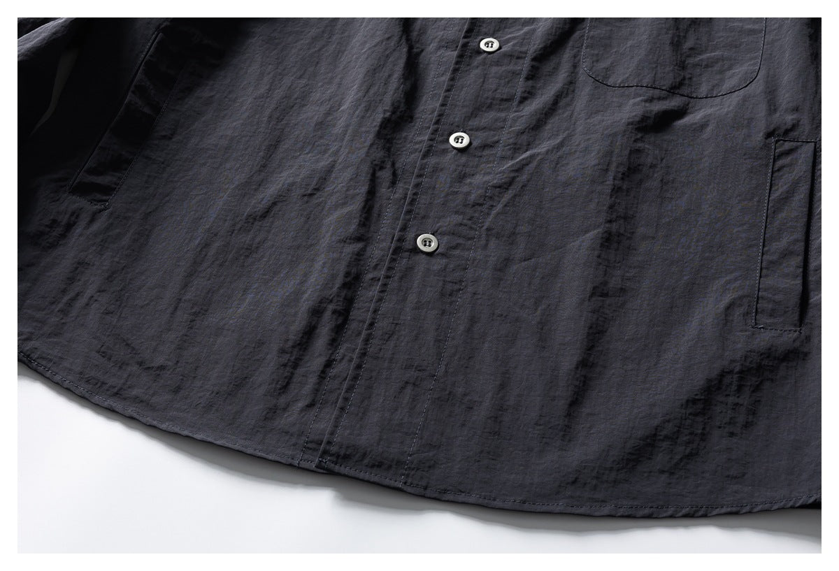 Cropped lower-front view of a dark charcoal shirt showing its button placket, curved hem, and side pockets.