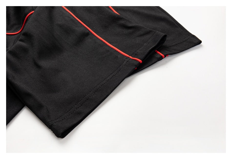 Close-up of a black shirt sleeve and hem with red piping and visible stitching.