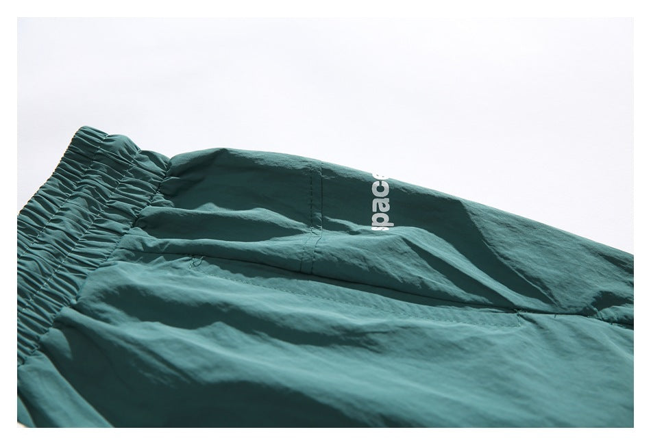 Close-up of teal shorts showing the elastic waistband, fabric seams, and partial white lettering.